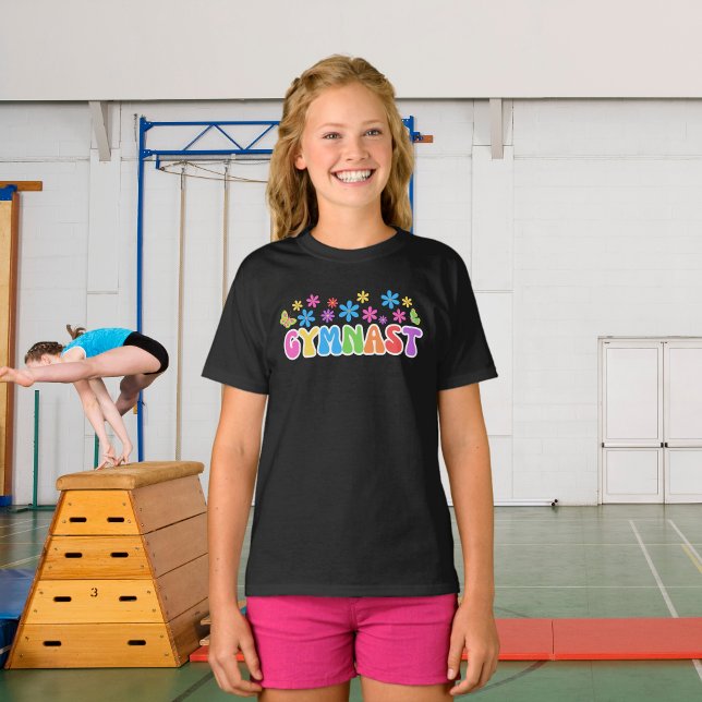 T-shirt do ginasta Retro | T-shirt temática "ginás (A young girl wearing gymnast black t-shirt with flower power style retro design. Gymnasium behind.)