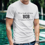 T-shirts É um trabalho difícil ser Bob<br><div class="desc">A Camisa Engraçada diz em letras negras,  "É um trabalho difícil ser BOB,  mas alguém tem que fazer isso". Personalize-o com o seu próprio nome ou personalize-o alterando as palavras. Faz um presente de Excelente! Vá em frente...  coloque um SMILE no rosto dele!</div>