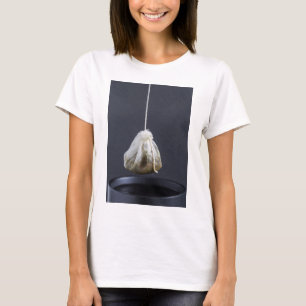 T-shirts O saco de chá está pendurado em uma xícara