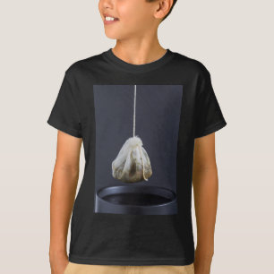 T-shirts O saco de chá está pendurado em uma xícara